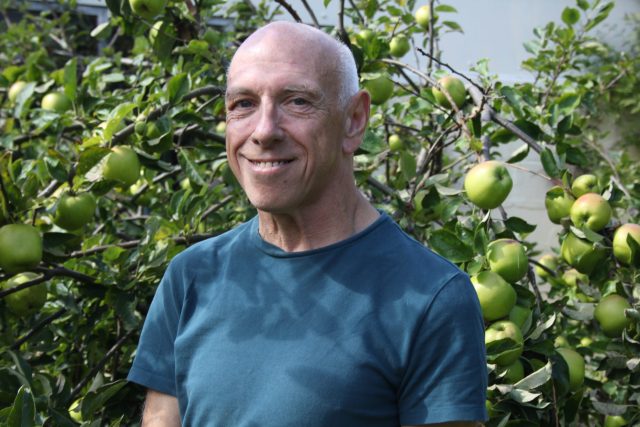David smiling in front of the apple tree in his garden